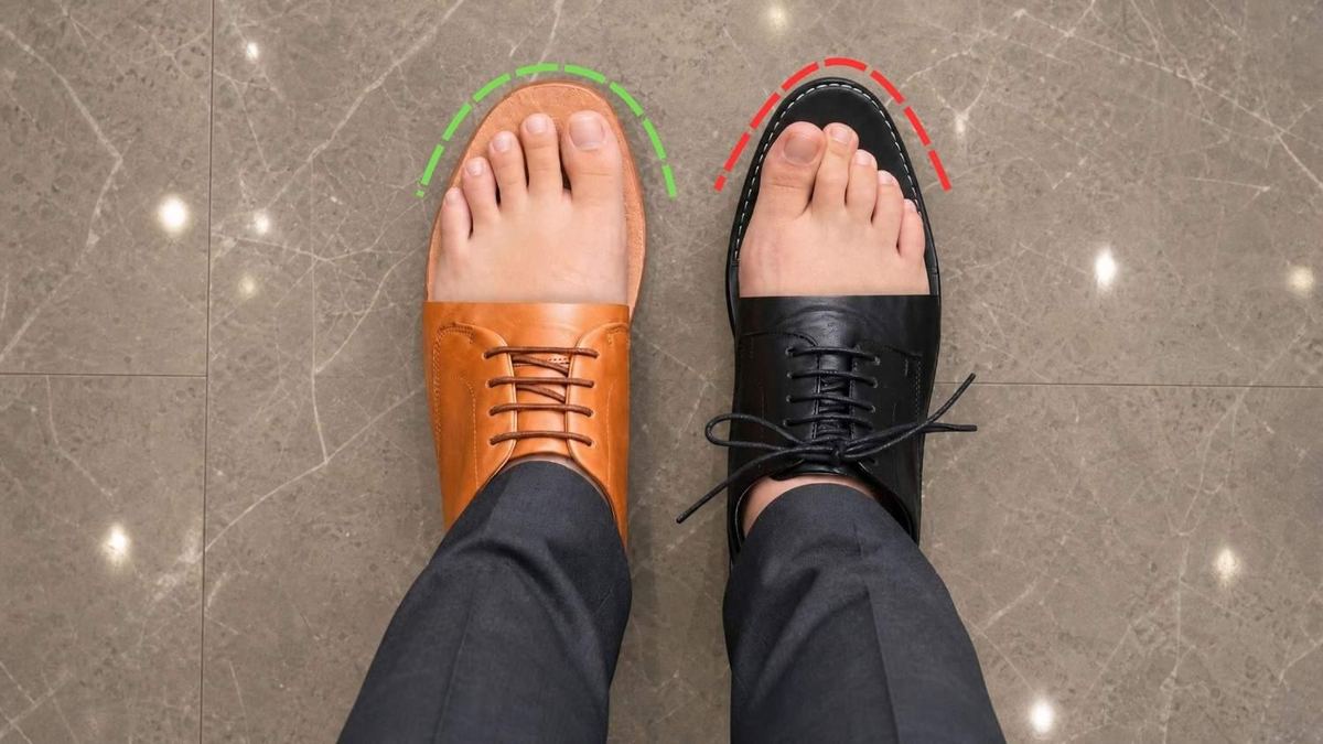 Top-down view of feet in a foot-shaped shoe beside a pointed dress shoe, showing the difference in toe room